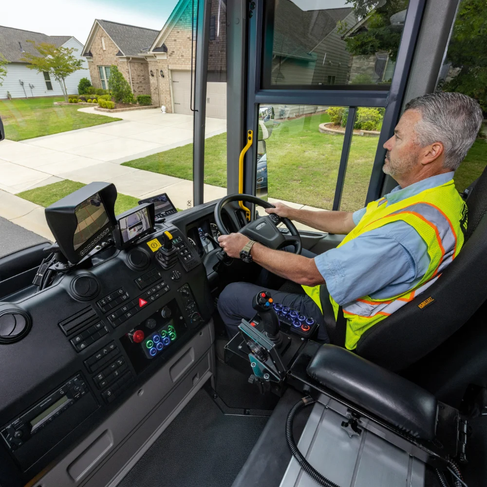 Driver inside Freightliner truck cabin with a view of suburban houses